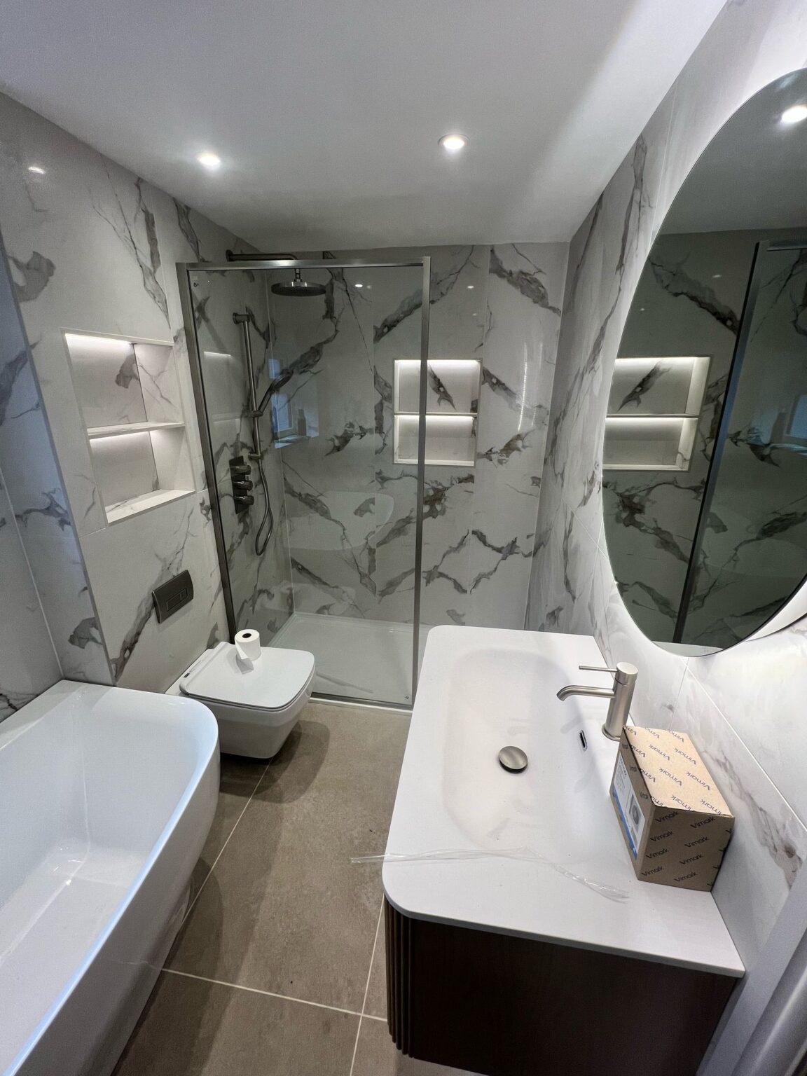 Luxury bathroom with marble-effect walls, walk-in shower, and modern bath