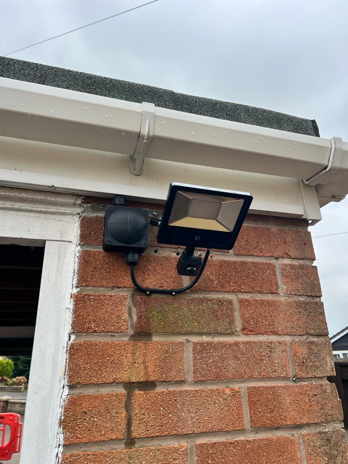Outdoor LED security light with PIR motion sensor installed on brick wall