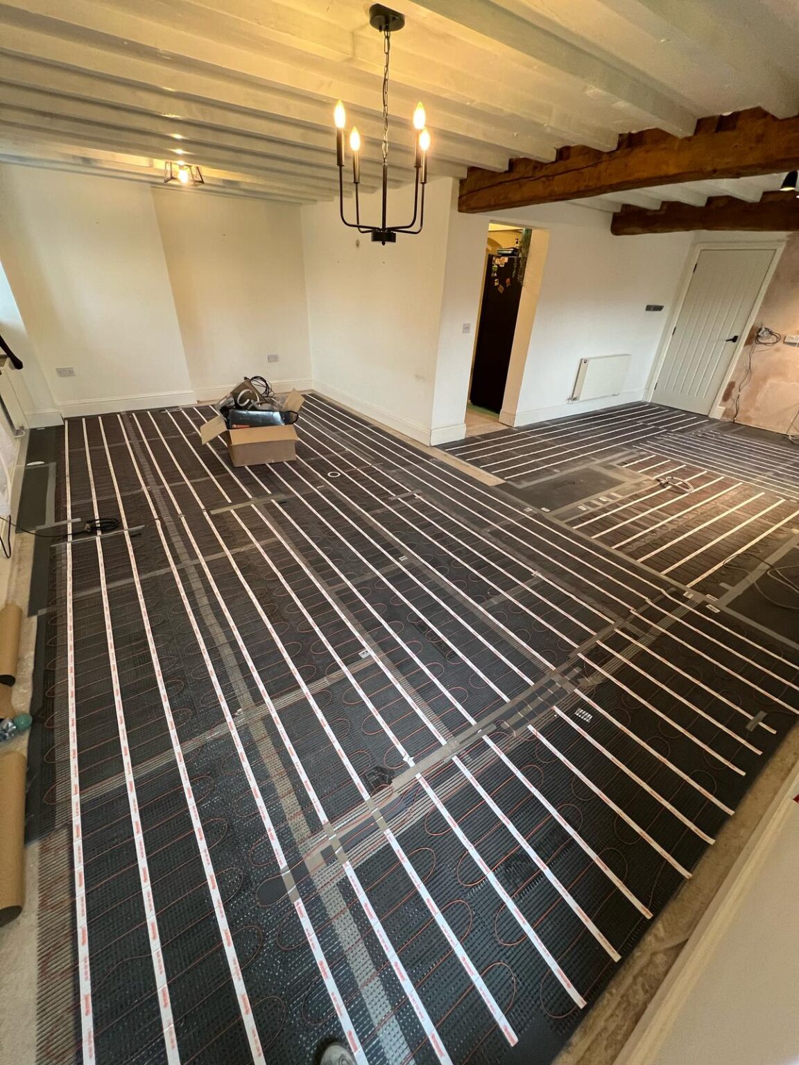 Electric underfloor heating installation in progress in rustic room