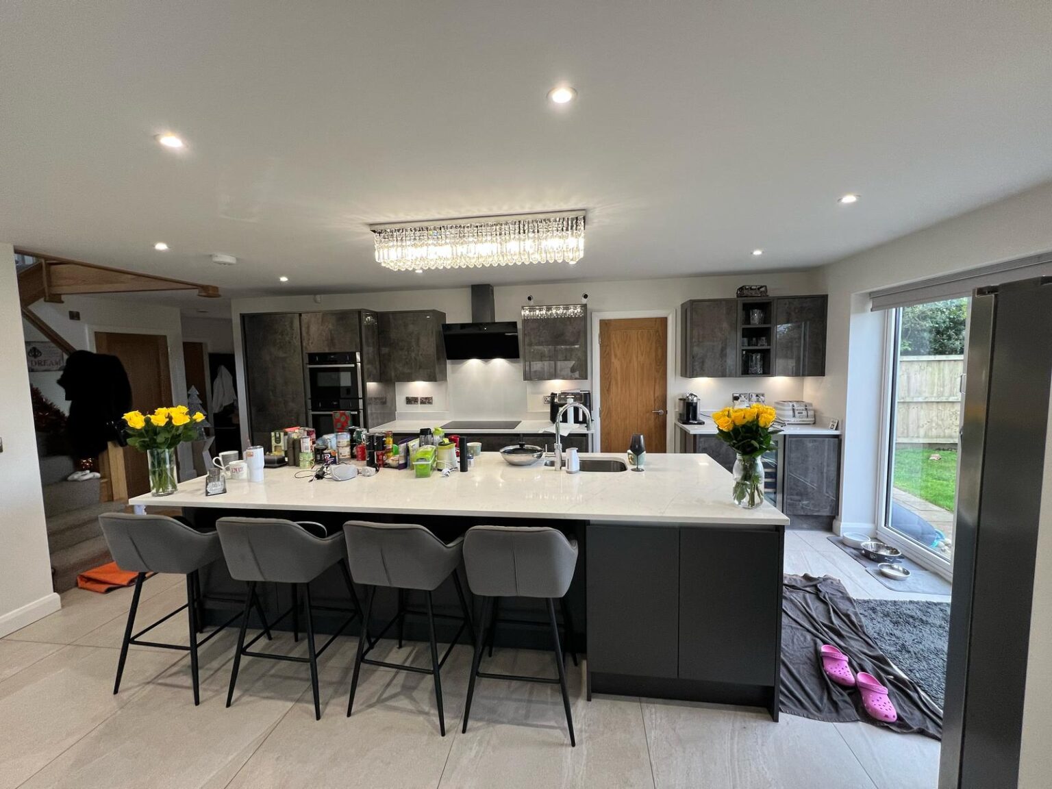 Modern open-plan kitchen with island, grey cabinetry, and crystal chandelier lighting