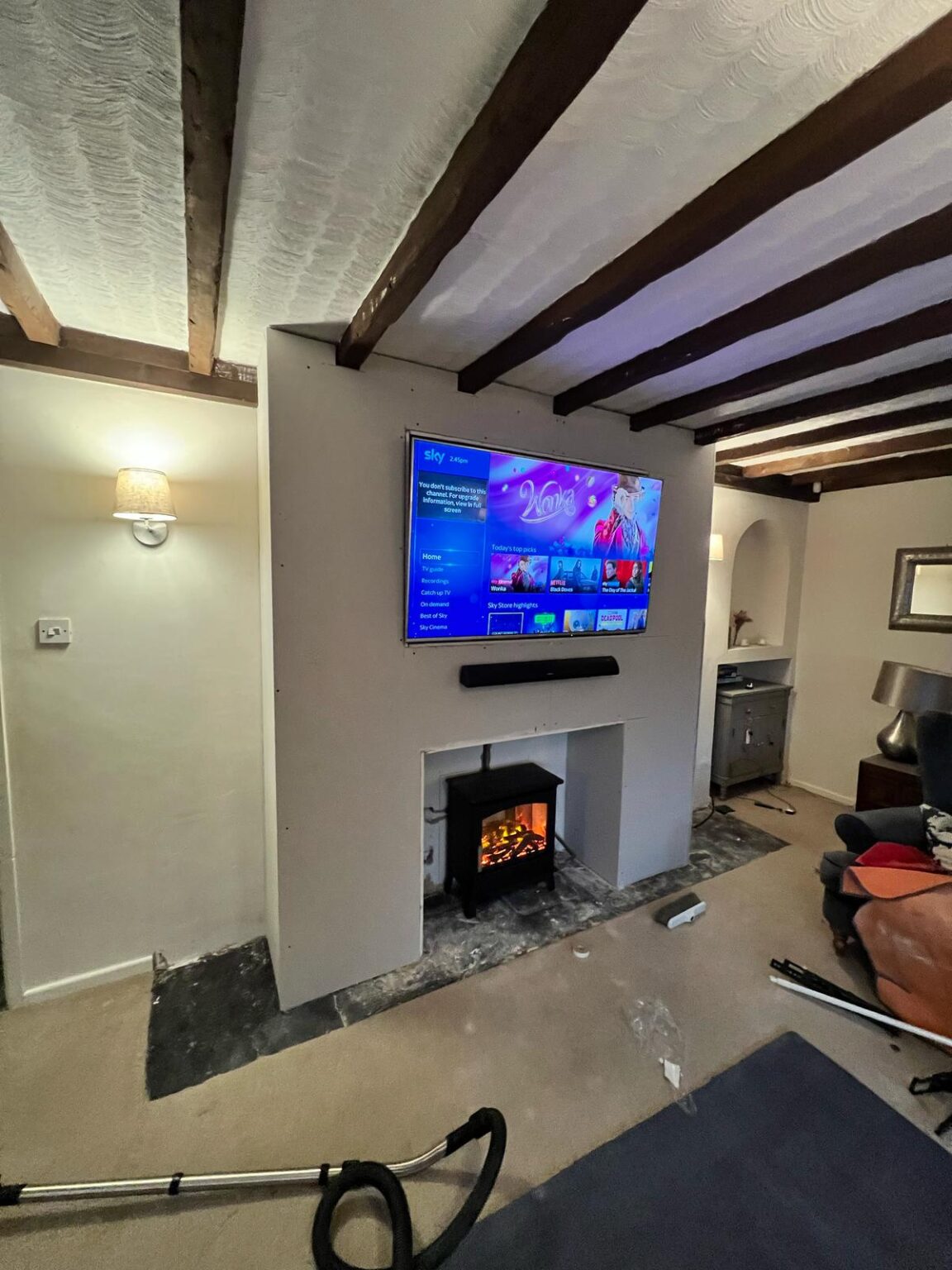 Living room with mounted TV, electric fireplace, and exposed ceiling beams
